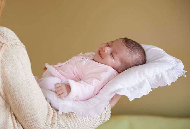 μωρό με ροζ φορμακι ξαπλωμένο σε στρωματακι αγκαλιας με λευκή θήκη