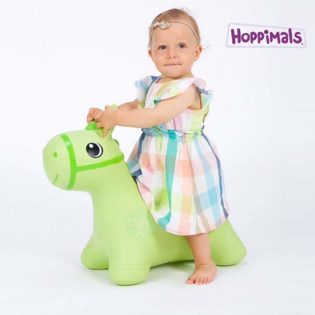 Ξανθό κοριτσάκι που φοράει καρό φόρεμα είναι πάνω σε φουσκωτό χοπ χοπ άλογο σε χρώμα πράσινο.