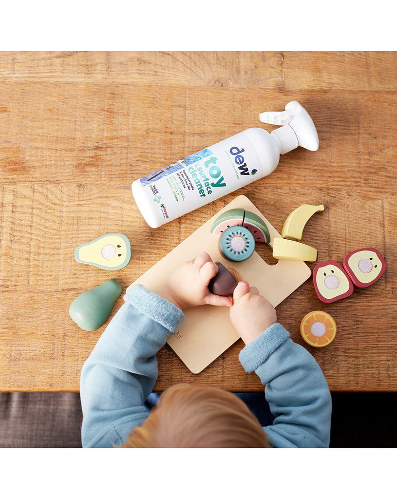 child playing with toys next to organic cleaning bottle